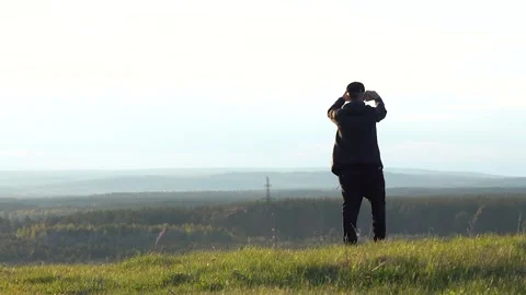 A man captures a scenic landscape with a camera at sunset, enjoying the peaceful Stock Footage 280291711
