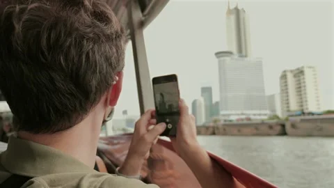 Man capturing city skyline on smartphone from boat. Stock Footage 257496777