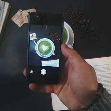 Man capturing an image of a Matcha latte with smartphone Stock Photos