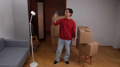 Man capturing moving day with smartphone selfie Stock Footage 309709413