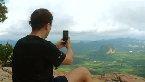 Man capturing scenic mountain landscape with smartphone Stock Footage 258204772