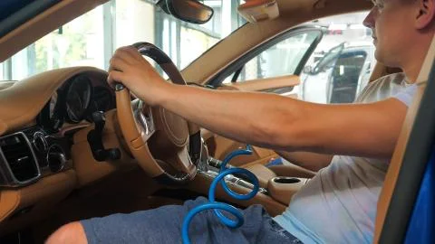 The man in the car dries from inside all parts of the car using a rag Stock Photos