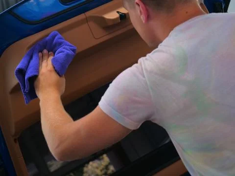 The man in the car dries from inside all parts of the car using a rag Stock Photos