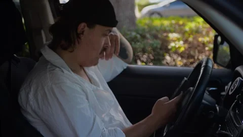 Man in car holding smartphone upright in front of steering wheel... Stock Footage 324632353