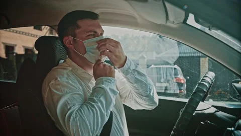 The man in the car puts on a disposable face mask. Video stock 150156383