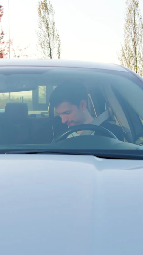 Man in a car, relaxing after work, with sunlight filtering through trees Stock Footage 318475660
