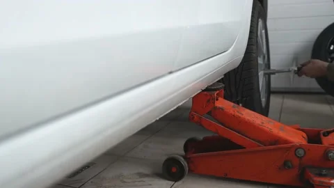 A man in a car service is changing the wheel of a white car, selective focus. Video stock 182916239