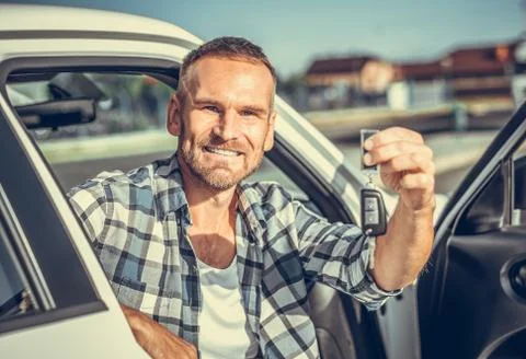 A man in a car shows a key. Stock Photos