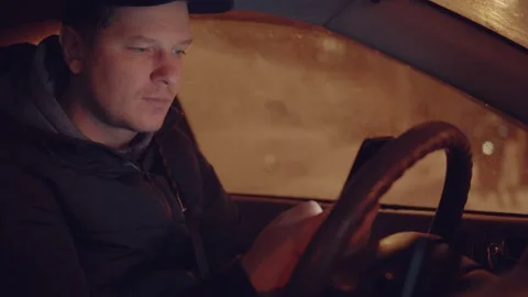 A man in a car is using a mobile phone at night Stock Footage 147668605