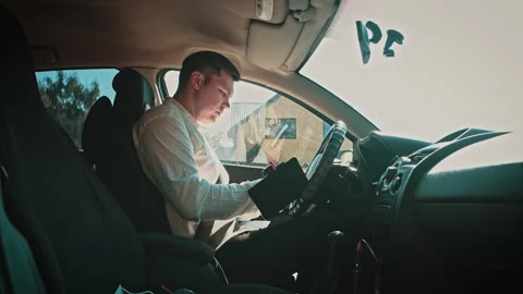 A man in a car writes information data into a notebook with a fountain pen. Stock Footage 150154389