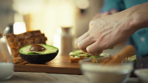 A man carefully assembles sandwiches on a kitchen table slicing fresh bread Stock Footage 331309356