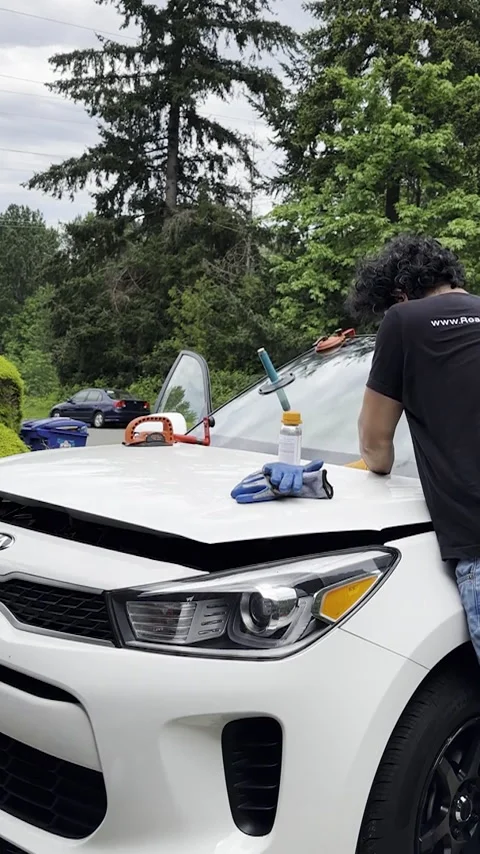Man carefully attaches new windshield to white car. Vertical shot Stock Footage 289298728