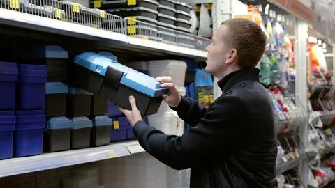 Man carefully choosing toolbox at hardware store, focusing on diy project. Shows Stock Photos