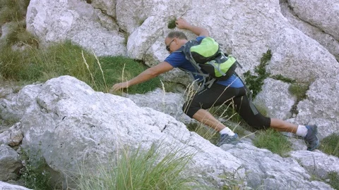 Man Carefully Climbing The Rocks On The Steep Mountain Terrain Stock Footage 93661243