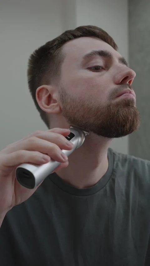 Man carefully contours beard with steady hold on trimmer 動画素材 333332149