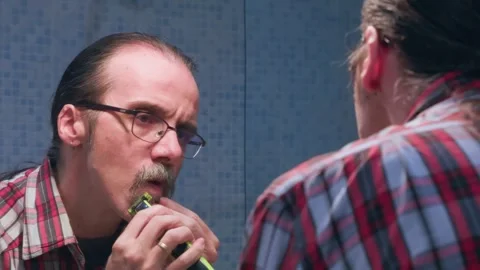 Man carefully detailing and defining his mustache line with an electric raz.. Stock Footage 327847851