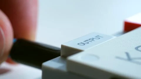 Man carefully inserts wire into output hole of digital device Stock Footage 277621065