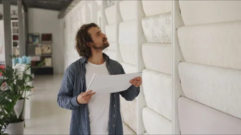 The man carefully inspects the range of wallpaper for further renovation Stock-Footage 144016022