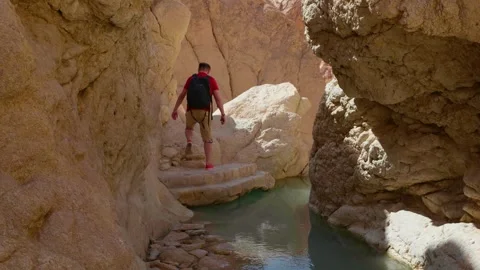 Man carefully passing the rocks in the river between high mountains. Stock Footage 296366355