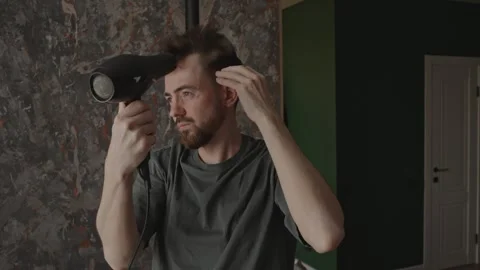 Man carefully shaping beard and hair indoors with natural light 動画素材 333332047
