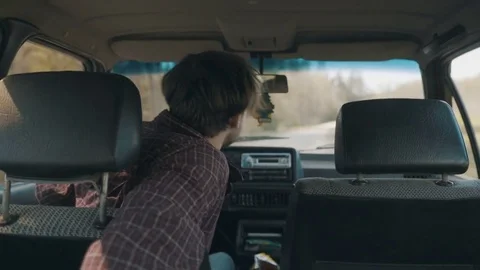 Man carelessly driving an old car and reaching for a snack on the backseat Stock Footage 83224733