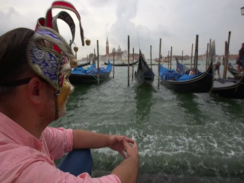 Man with a carnival mask looking at gondolas in San Marco, Venice, Italy Stock Footage 69935196