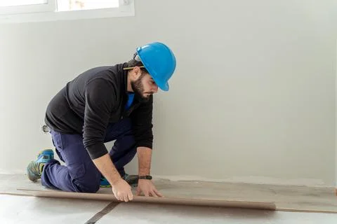 Man Carpenter assembling laminate flooring. House floor renovation Stock Photos