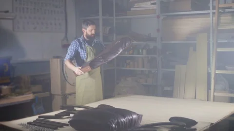 Man carpenter in a dark authentic workshop collects furniture Stock Footage 98545168