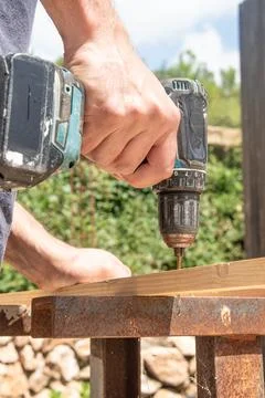 Man Carpenter through drilling Use Cordless Drill In Wooden Board On sawhorse Stockfoto's