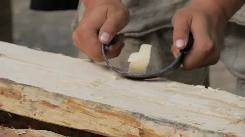 Man carpenter using drawknife to shape and smooth wood board - slow motion Stock Footage 141388162