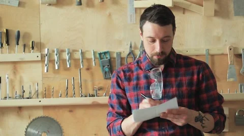 Man in the carpenter's workshop writing a draft on paper Video stock 61361229