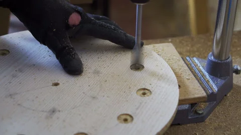 A man in a carpentry workshop drills a board. Manufacture of wooden handicrafts. Stock-Footage 240398853