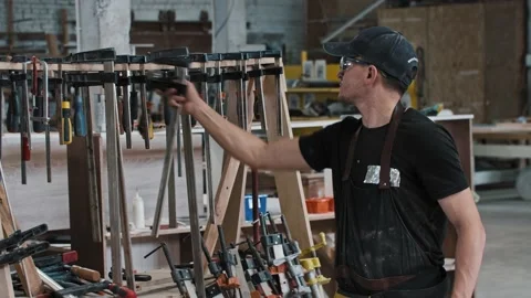 Man in a carpentry workshop takes an instrument - looking in the camera Stock Footage 157036028