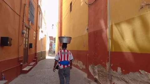 Man carries a bucket over head walking on the street Stock Footage 157738752