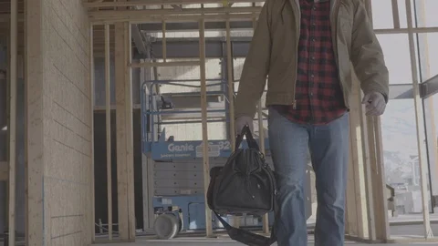 A man carries a tool bag through a work site Stock Footage 102124604