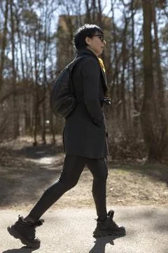 A man carrying a backpack is walking down a narrow path in the woods Stock Photos