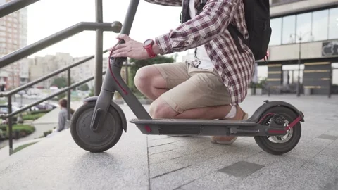 Man Carrying folded E-Scooter in hand on stairs near building. Moving by eco Stock Footage 138515542