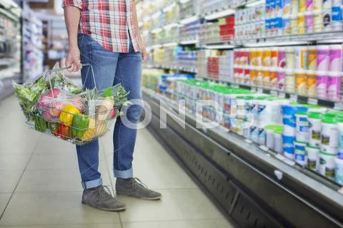 Man carrying full shopping basket in grocery store Stock Photos