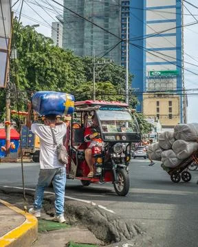 Man carrying a large wrapped bundle on his head beside a motorized tricycle on a 스톡 사진