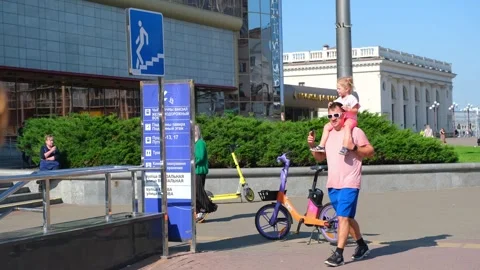 Man carrying small child on his shoulders walking past urban street signs. Stock Footage 337529705