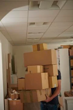 A man carrying a stack of boxes across a store room. 写真素材