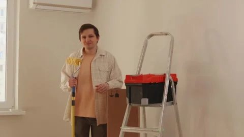 Man carrying toolbox, paint roller, and cable into renovated room Stock Footage 346159426