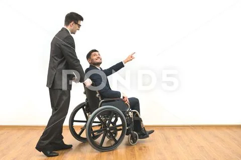 The man carrying a wheelchair with a disabled on the white wall background Stock Photos