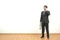 The man with a case phones on the white wall background Photo