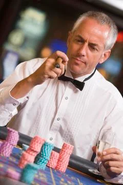 Man in casino playing roulette and smoking cigar (selective focus) Stock Photos