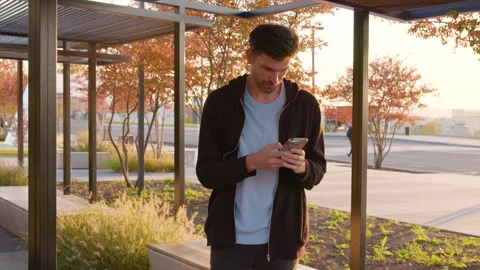 Man in casual attire using smartphone in a vibrant shopping district, surrounded Stock Footage 317702973
