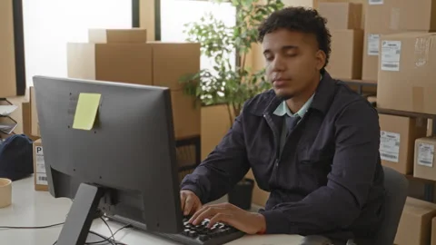 Man in casual jacket pointing hand at computer amid stacked parcels and shi.. Stock Footage 347849027