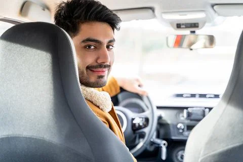 Man casually dressed with hand on driving wheel looking on backseat in camera Stock Photos