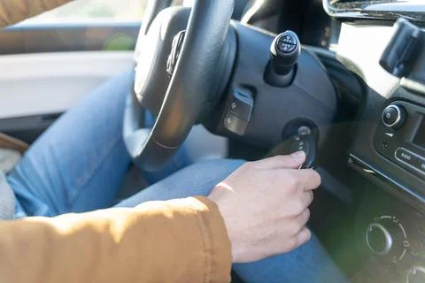 Man casually dressed with hands holding driving wheel starting engine with key Foto stock