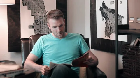 Man Casually Reading Magazine in Leather Chair Stock Footage 39653039